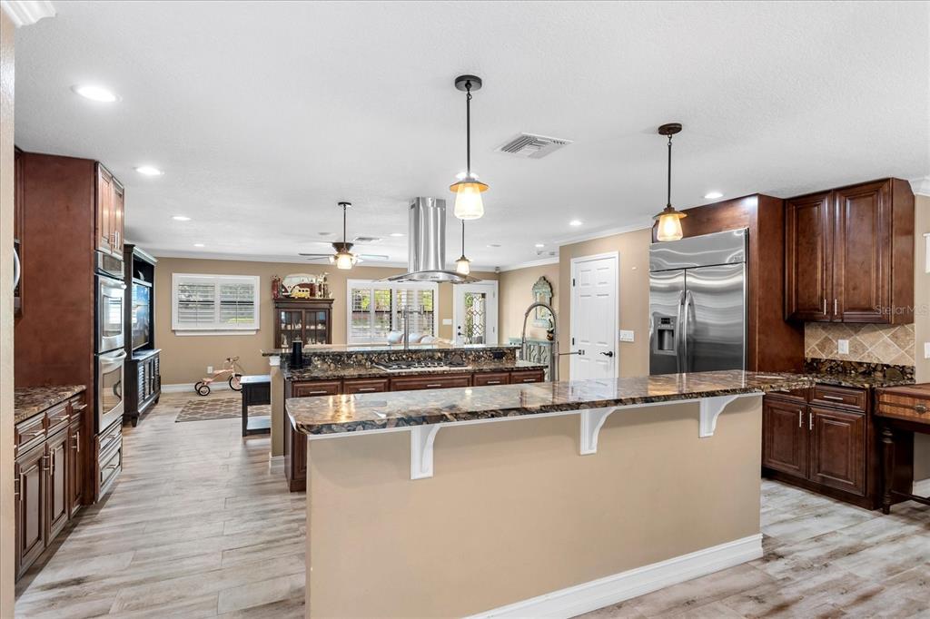 A kitchen features dark wood cabinets, granite countertops, a center island, and stainless steel appliances — 524 EDEN PARK, ALTAMONTE SPRINGS, FL