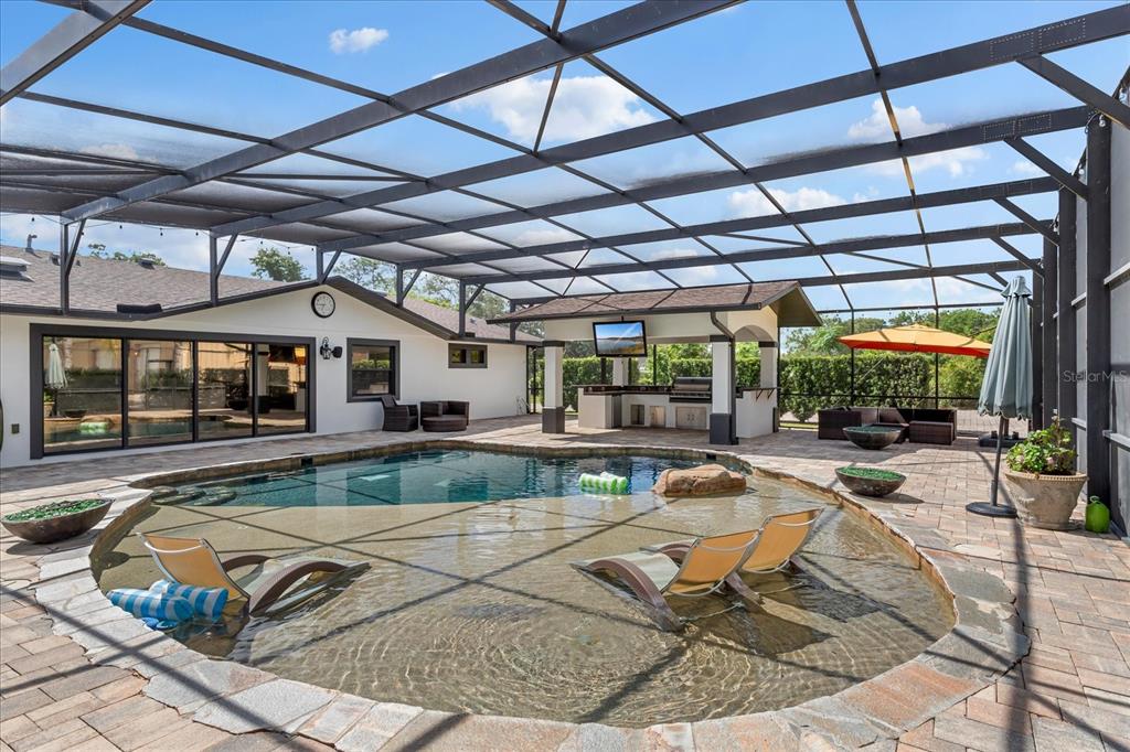 A screened-in patio features a swimming pool with a tanning ledge and an outdoor kitchen — 524 EDEN PARK, ALTAMONTE SPRINGS, FL