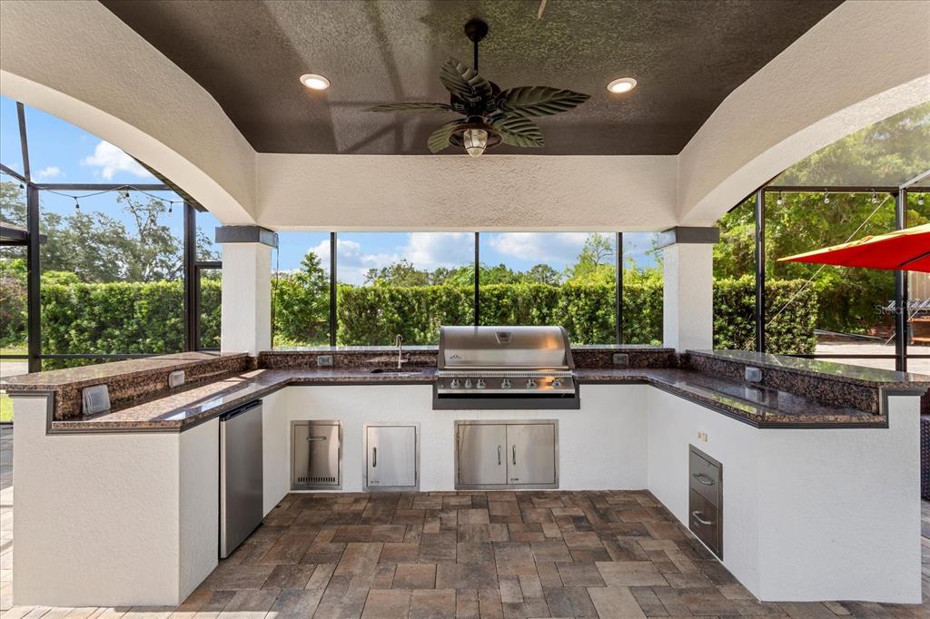 An outdoor kitchen with a stainless steel grill, granite countertops, and a ceiling fan — 524 EDEN PARK, ALTAMONTE SPRINGS, FL