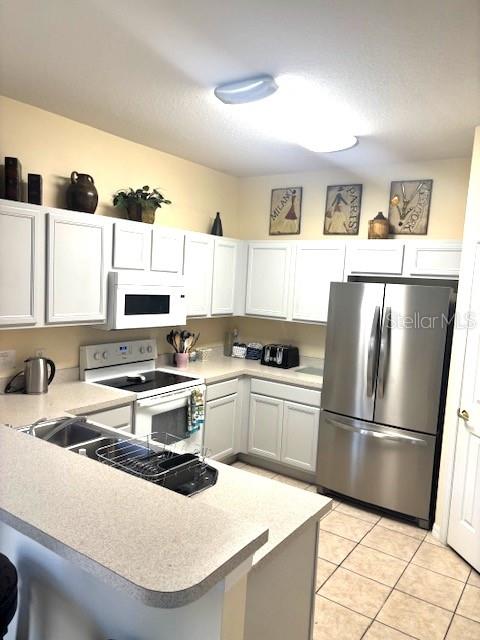 A kitchen features white cabinets, stainless steel appliances, and a light-colored countertop — 644 MONTARA DR, DAVENPORT, FL