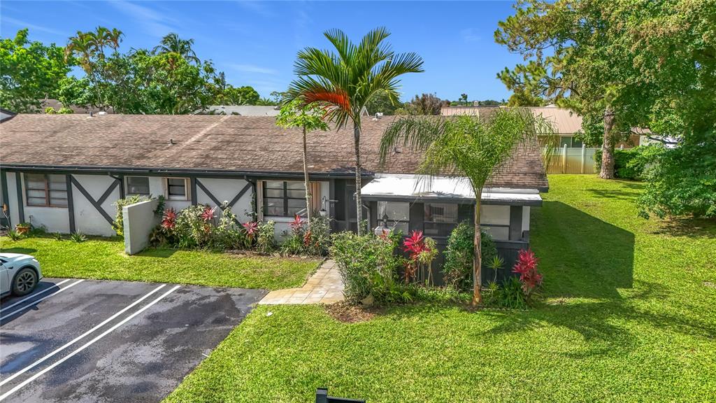 An exterior view of a single-story townhouse with a paved walkway and palm trees — 55 SEMINOLE DRIVE, ROYAL PALM BEACH, FL