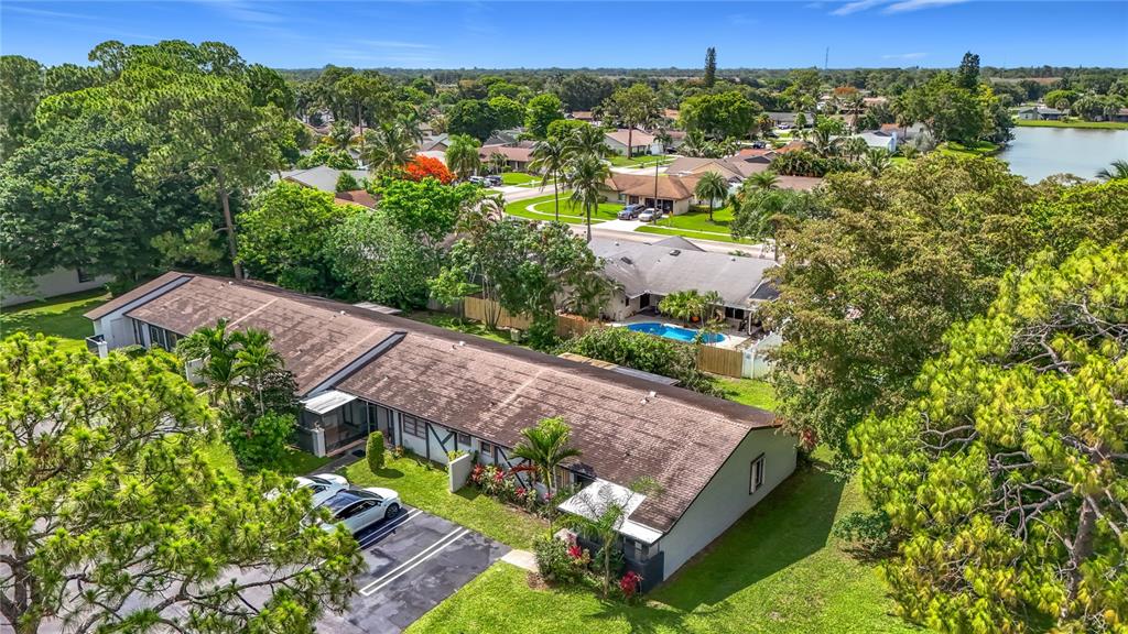 An aerial view shows a single-story residential building with a parking lot and surrounding trees — 55 SEMINOLE DRIVE, ROYAL PALM BEACH, FL