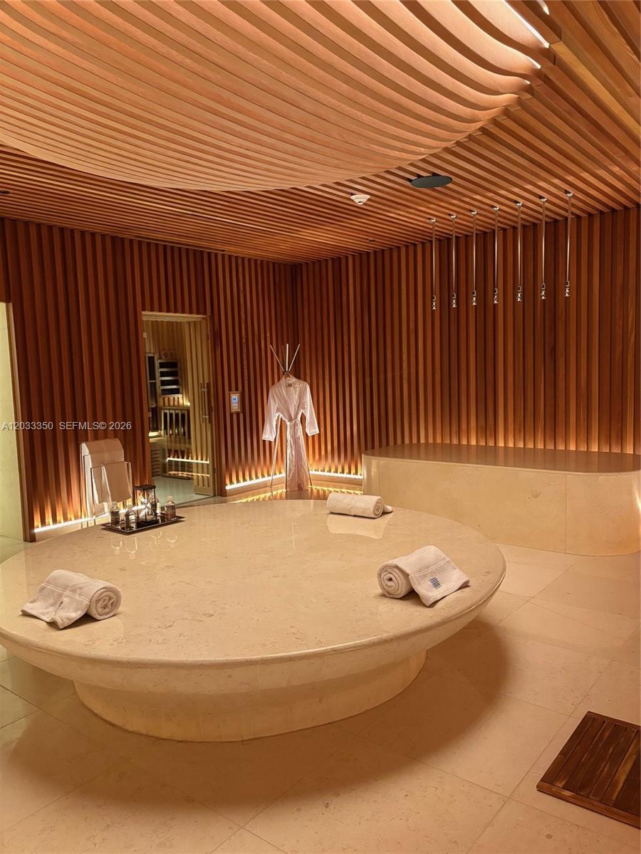 A spa room features a large circular stone table, wood-slatted walls, and a sauna — MIAMI BEACH, FL