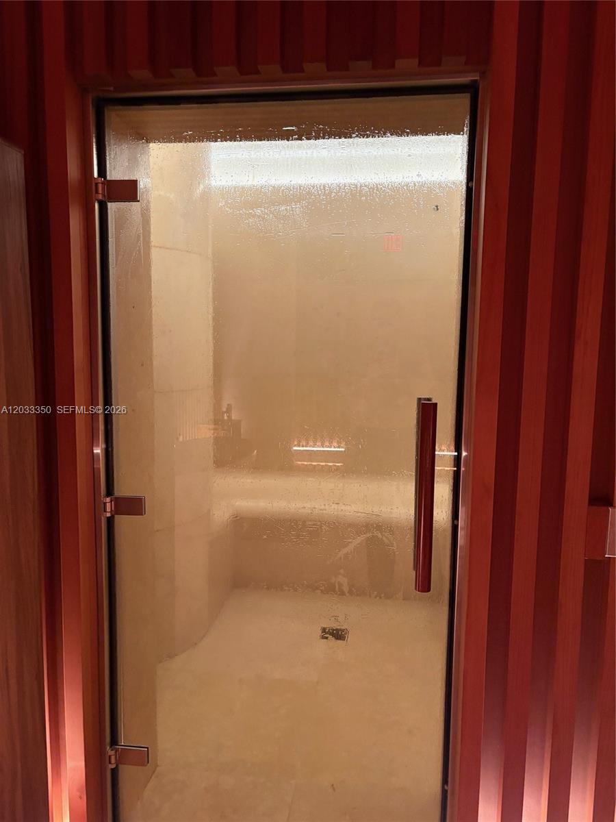 A glass-doored steam shower is framed by vertical wood paneling — MIAMI BEACH, FL
