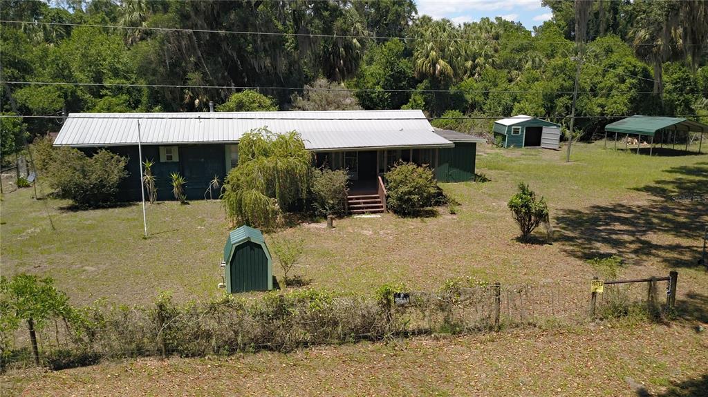 An aerial view shows a single-story house with a metal roof, outbuildings, and fenced yard — 11291 SE 202ND LANE, INGLIS, FL
