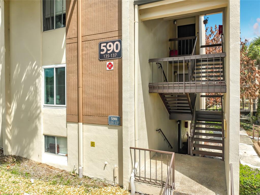 An exterior view of a multi-story apartment building with an outdoor staircase and unit signage — 590 ORANGE DRIVE UNIT 136, ALTAMONTE SPRINGS, FL