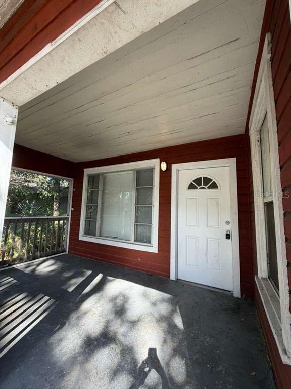 A covered porch with red siding, a white front door, and a large window — 3404 E 33RD AVENUE, TAMPA, FL