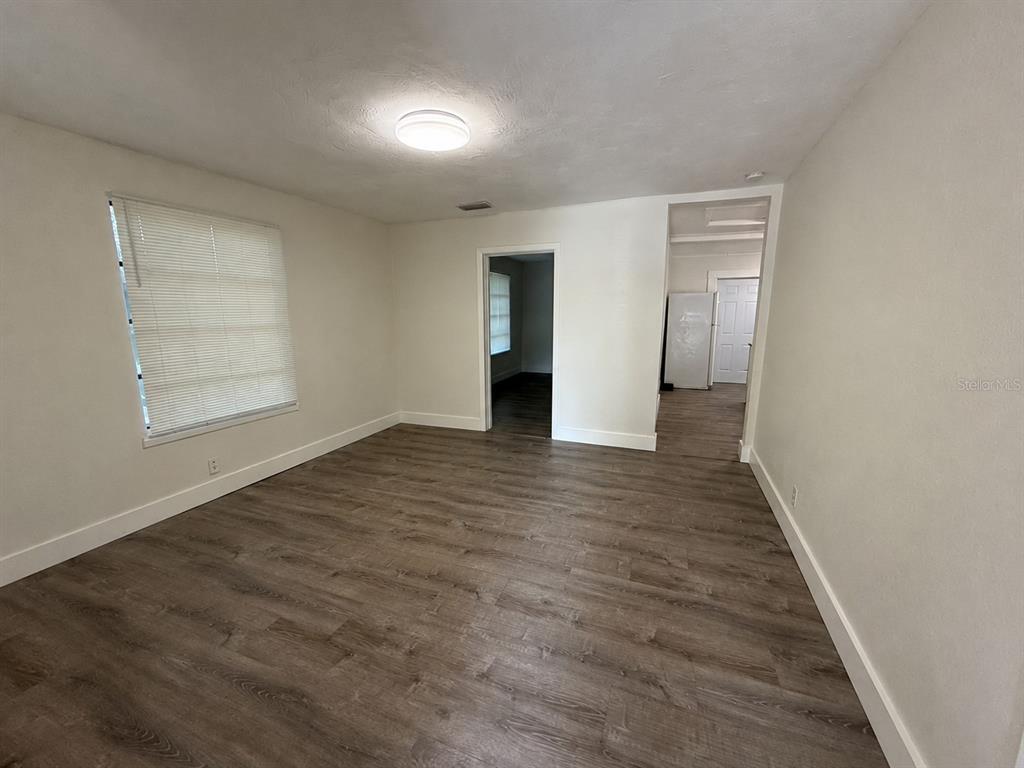 An empty room features wood-look flooring, white walls, a ceiling light, and two doorways — 3404 E 33RD AVENUE, TAMPA, FL