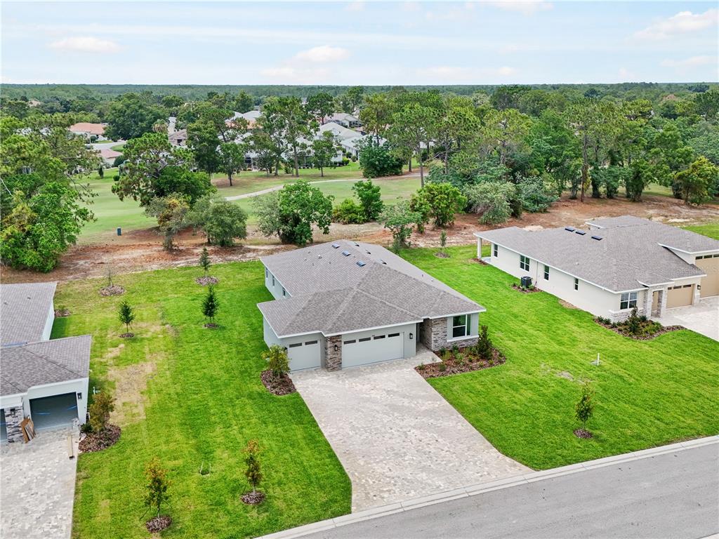 An aerial view shows a single-story house with a paved driveway and a grassy yard — 9143 PLAYERS DRIVE, WEEKI WACHEE, FL
