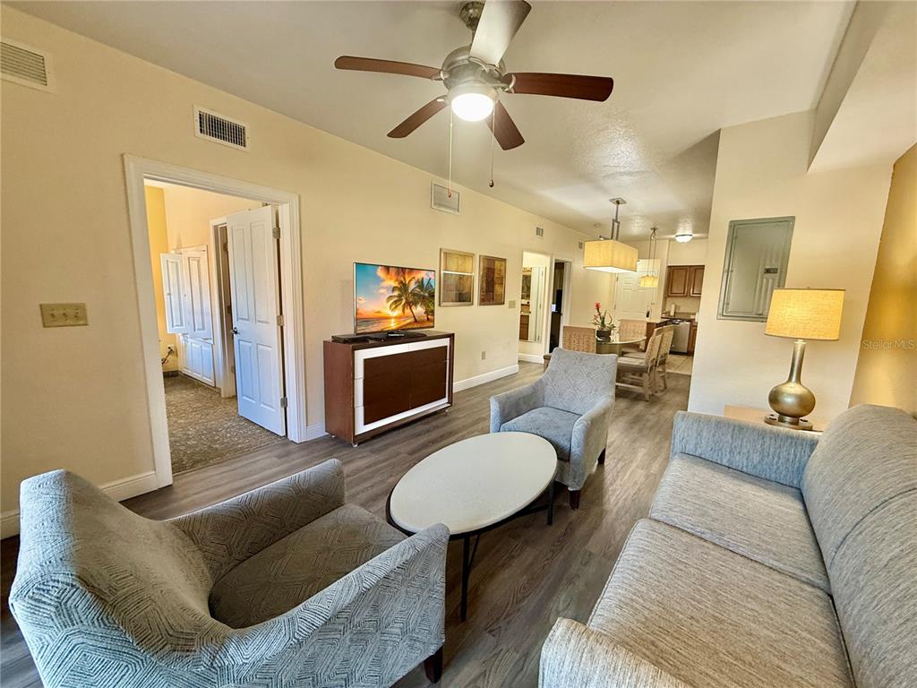A living room features light wood-look flooring, a ceiling fan, and a dining area beyond — 12539 FLORIDAYS RESORT DRIVE UNIT 107D, ORLANDO, FL