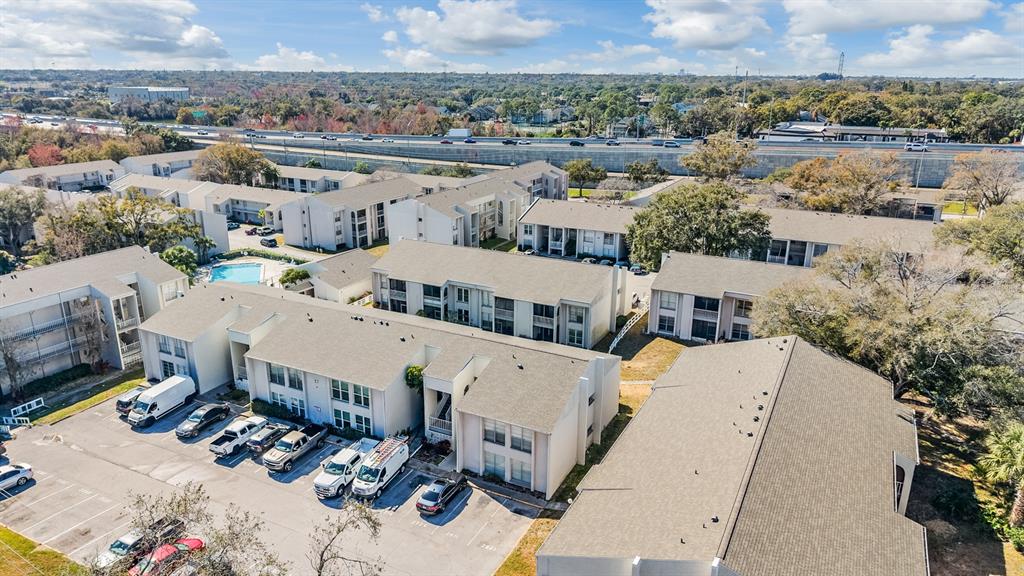 An aerial view shows multiple apartment buildings with parking lots and a nearby highway — 2625 STATE ROAD 590 UNIT 2714, CLEARWATER, FL