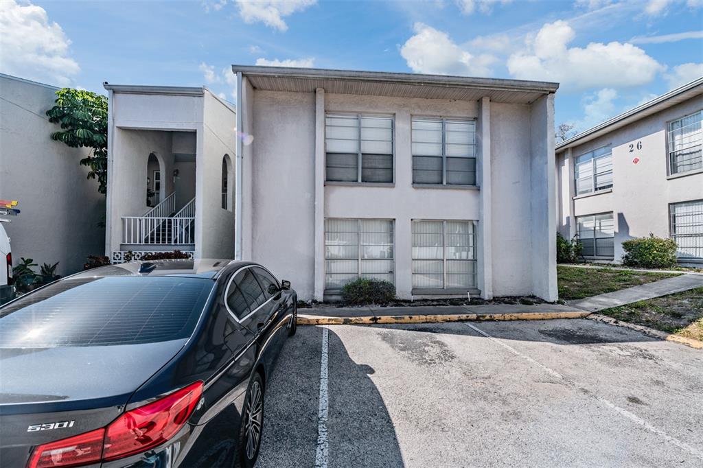 A two-story apartment building exterior features a parking space with a black sedan parked — 2625 STATE ROAD 590 UNIT 2714, CLEARWATER, FL