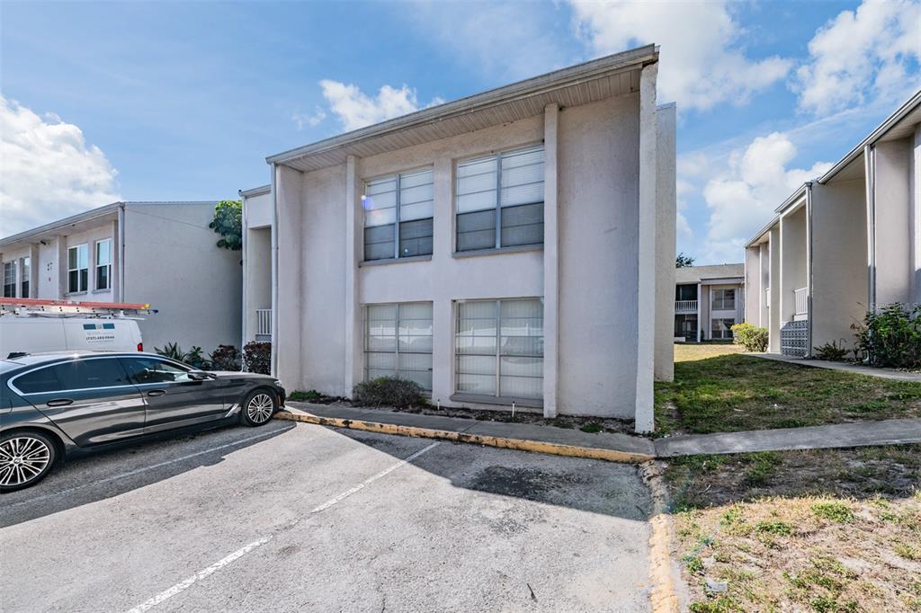 A two-story apartment building exterior with a parked car and a white service van — 2625 STATE ROAD 590 UNIT 2714, CLEARWATER, FL