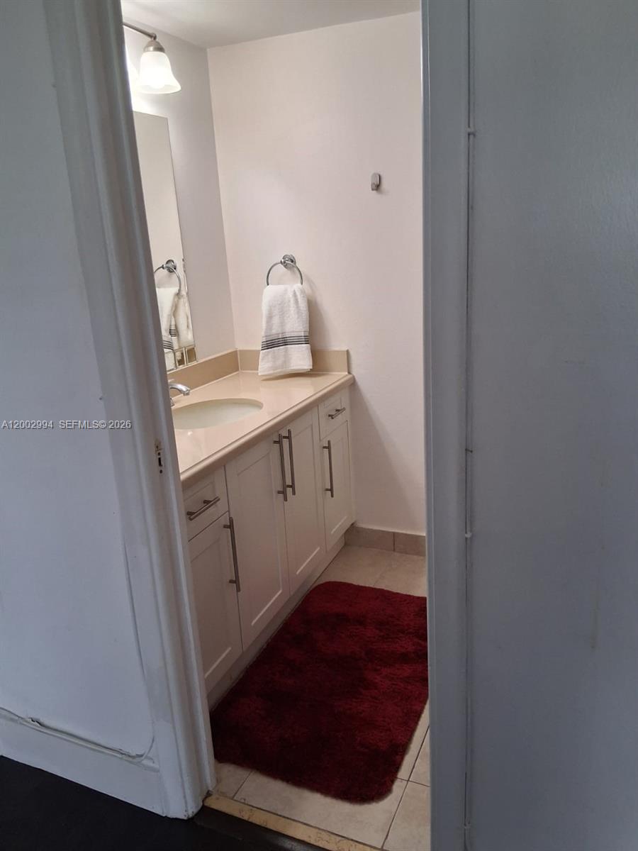 A bathroom features a white vanity with a beige countertop and a red floor mat — 301 NE 14th Ave # 202, Hallandale Beach FL 33009, HALLANDALE BEACH, FL