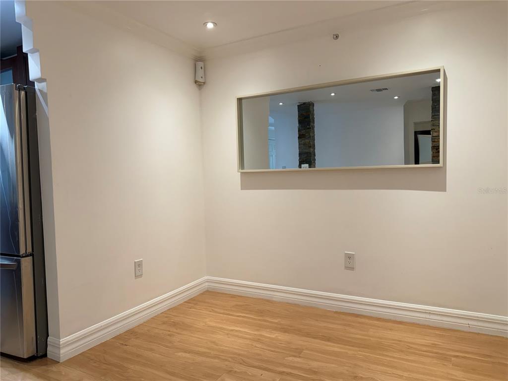A dining area features light wood flooring, white walls, and a large rectangular wall mirror — 18593 BRIDLE CLUB DRIVE, TAMPA, FL