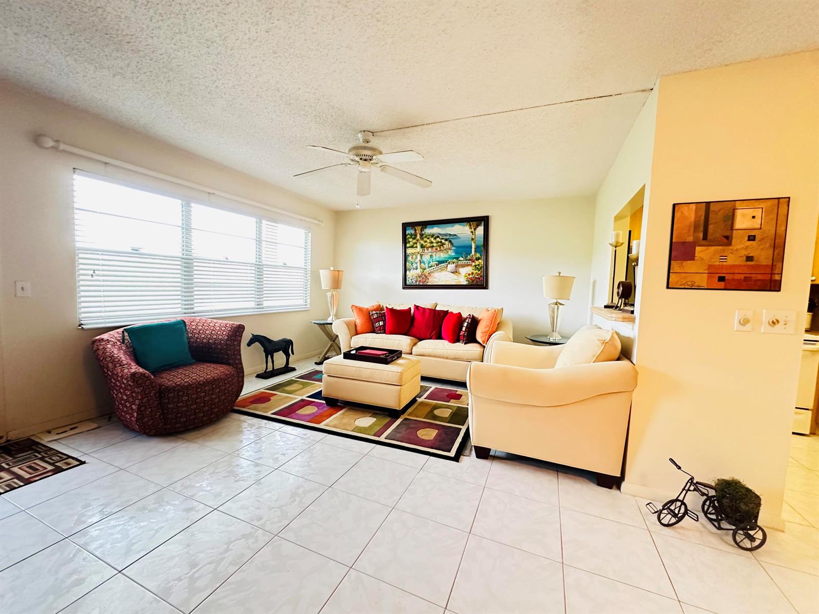 A living room features tiled floors, a patterned armchair, a sofa, and a ceiling fan — 4038 Berkshire B # 4038, Deerfield Beach FL 33442, DEERFIELD BEACH, FL
