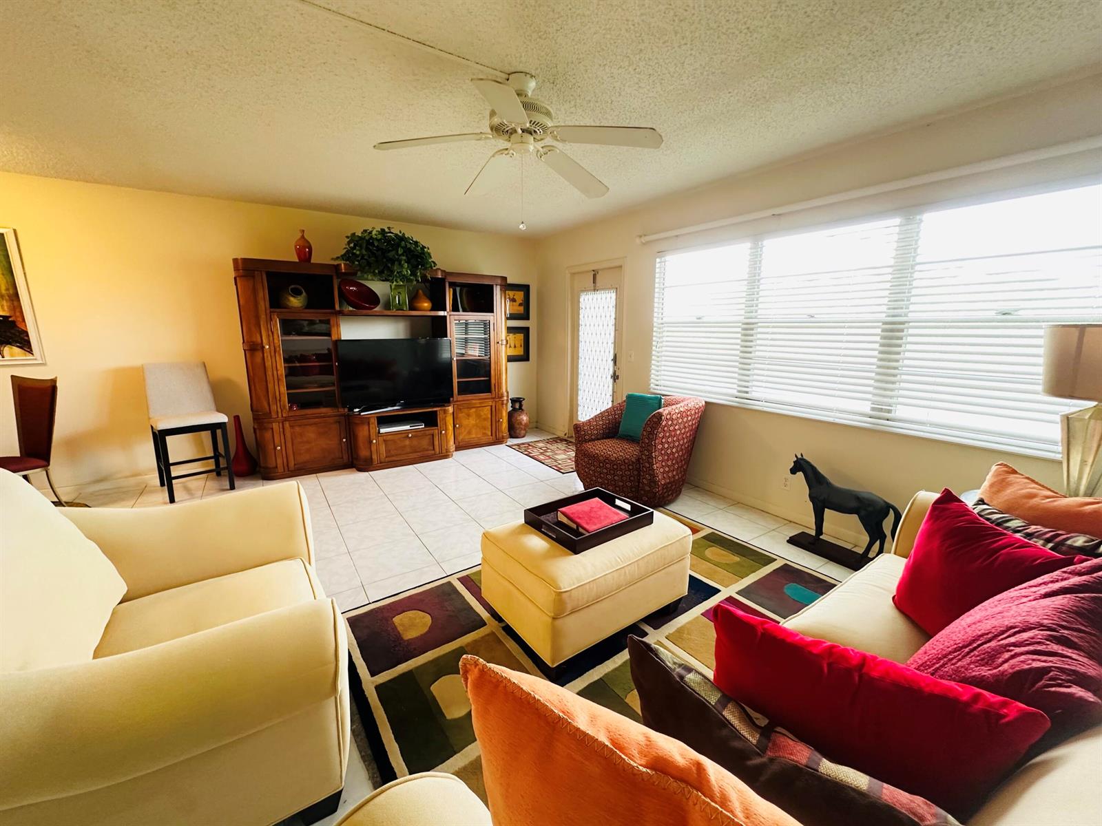 A living room features a wooden entertainment center, a patterned area rug, and seating furniture — 4038 Berkshire B # 4038, Deerfield Beach FL 33442, DEERFIELD BEACH, FL