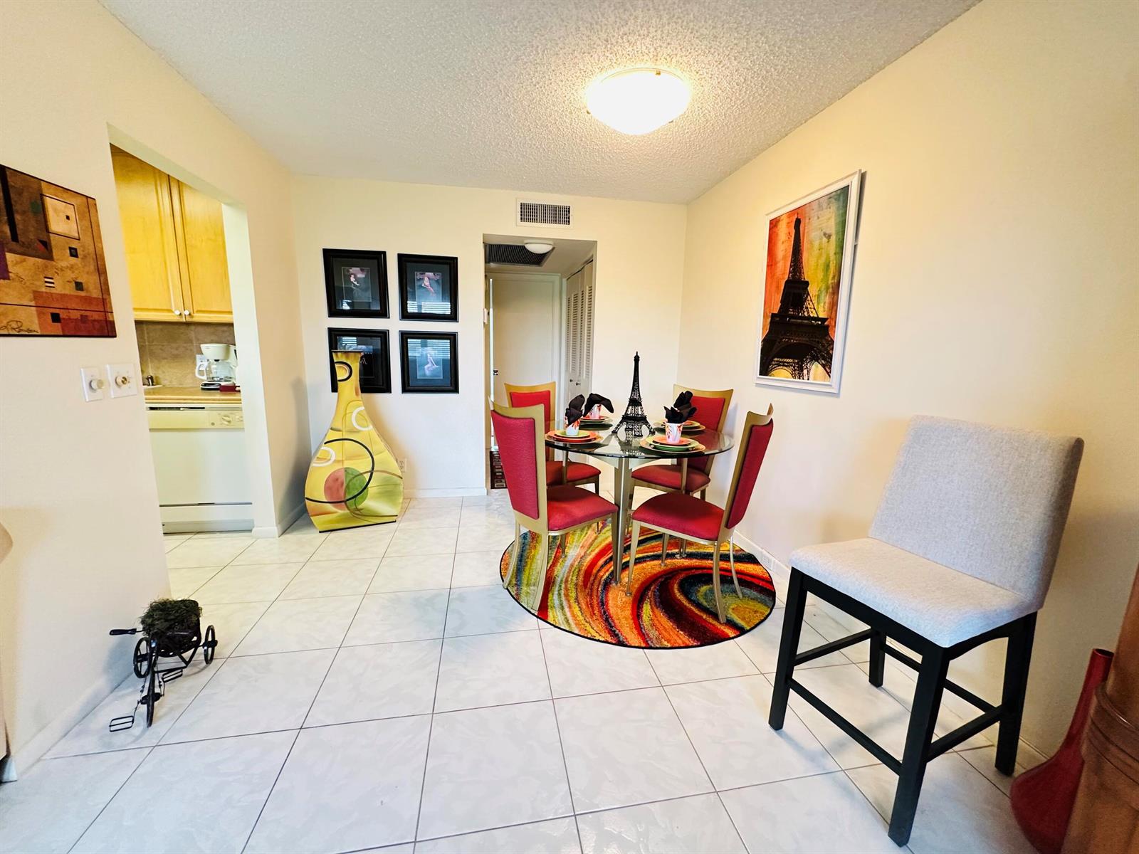 A dining area features a glass table with red chairs, a colorful rug, and tiled floors — 4038 Berkshire B # 4038, Deerfield Beach FL 33442, DEERFIELD BEACH, FL