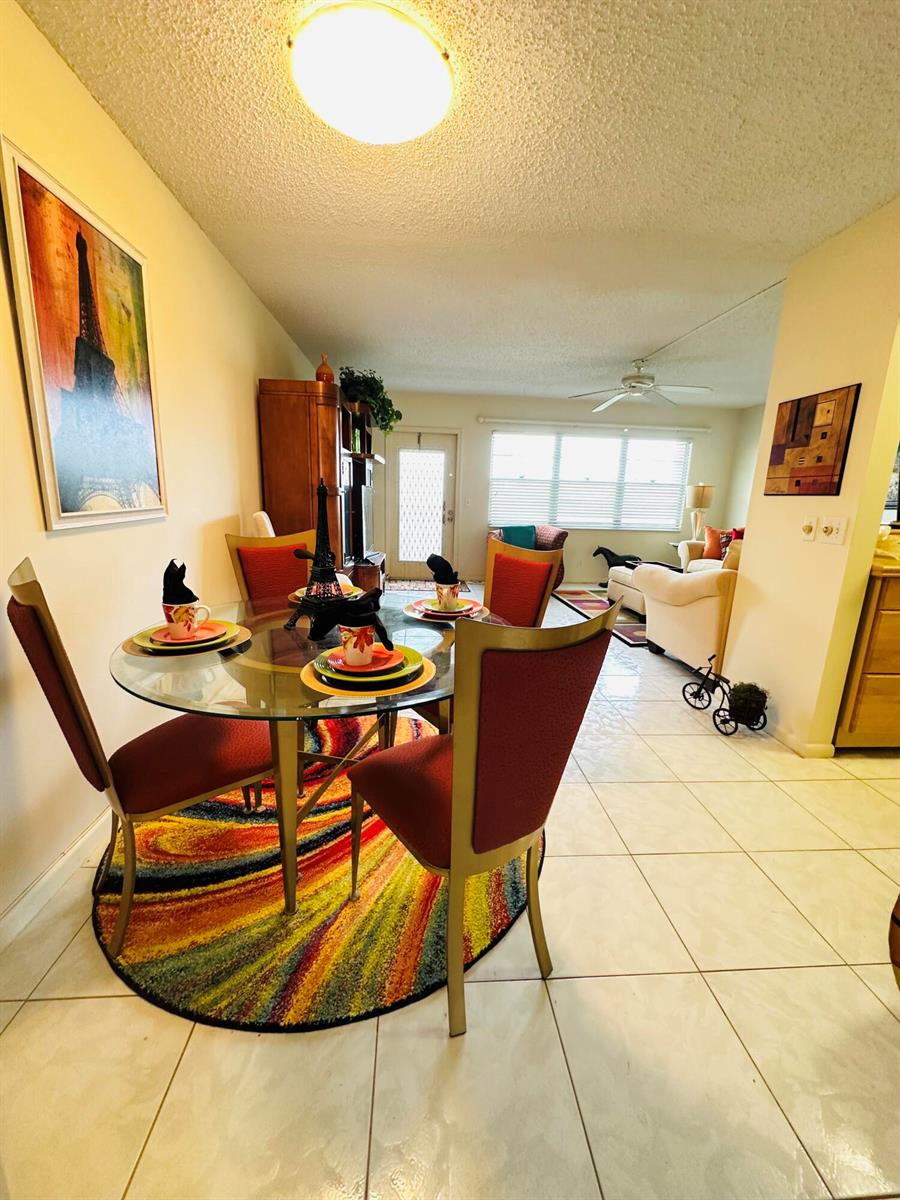 A dining area with a glass table and colorful rug opens into a living room — 4038 Berkshire B # 4038, Deerfield Beach FL 33442, DEERFIELD BEACH, FL