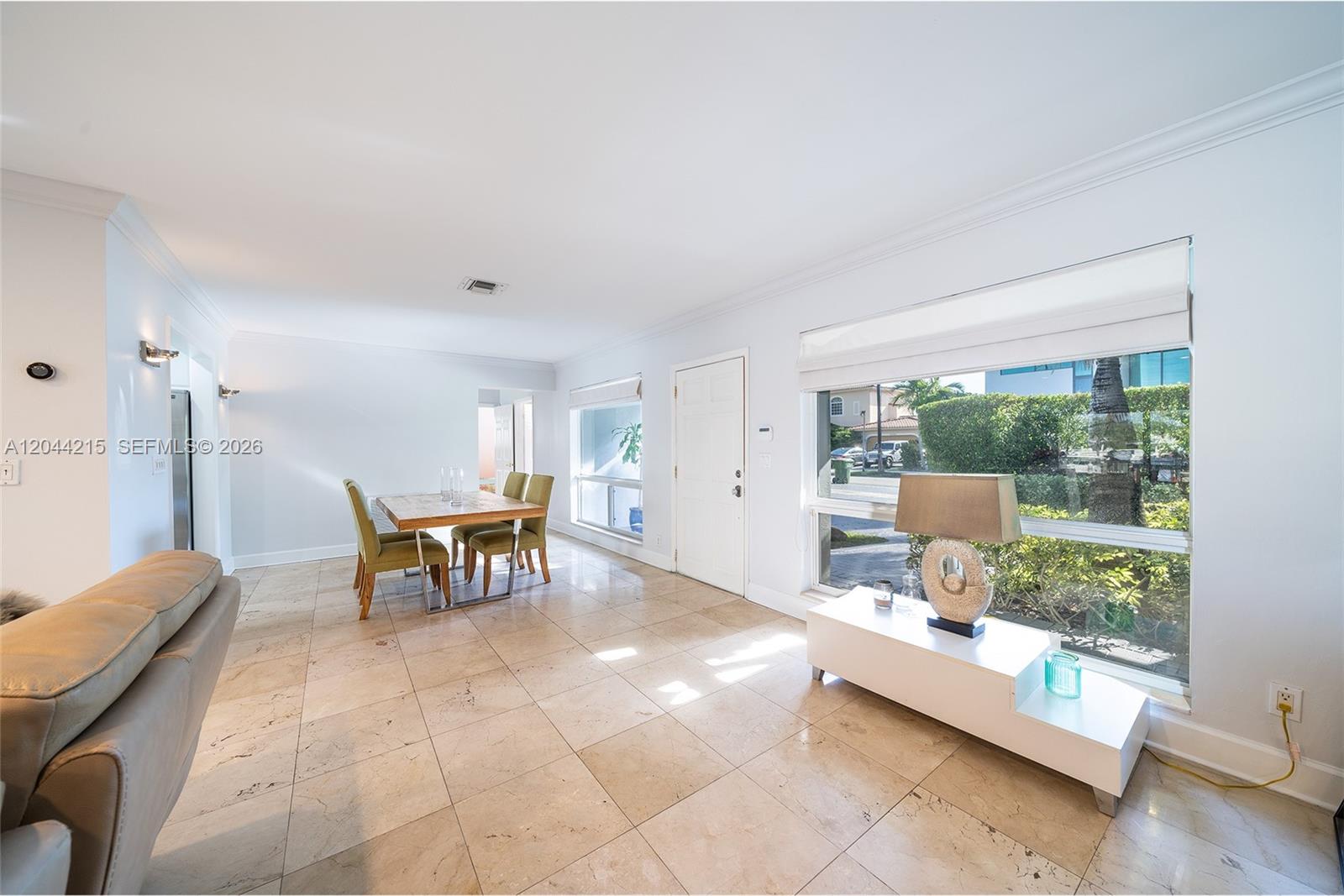 A dining area and living space feature light tile flooring, white walls, and large windows — 13140 Coronado Dr, North Miami FL 33181, NORTH MIAMI, FL