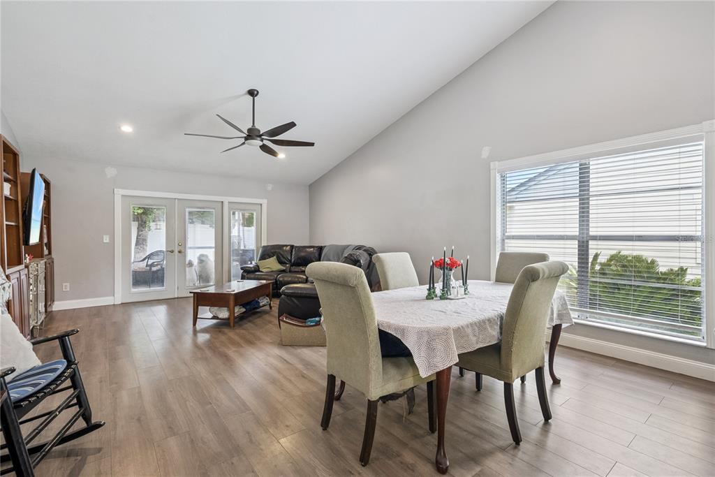 A living and dining area with wood-look flooring, vaulted ceilings, and a sliding glass door — 1009 MCCULLY COURT, OVIEDO, FL