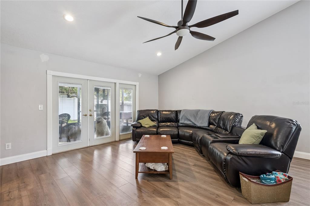 A living room features a dark leather sectional, wooden coffee table, and sliding glass doors — 1009 MCCULLY COURT, OVIEDO, FL