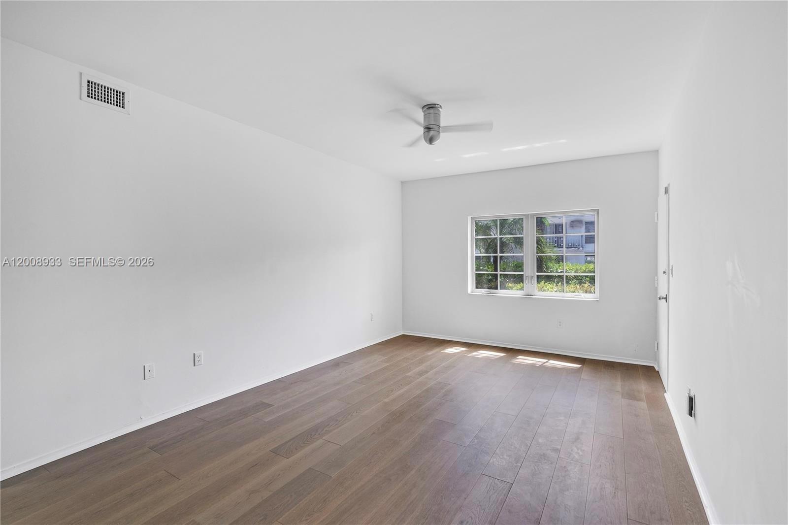 An empty bedroom features white walls, wood-look flooring, a ceiling fan, and a window — 1600 Michigan Ave # 2, Miami Beach FL 33139, MIAMI BEACH, FL