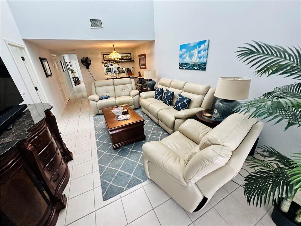 A living room features cream leather sofas, a wooden coffee table, and a blue rug — 4212 126TH STREET W UNIT 407, CORTEZ, FL