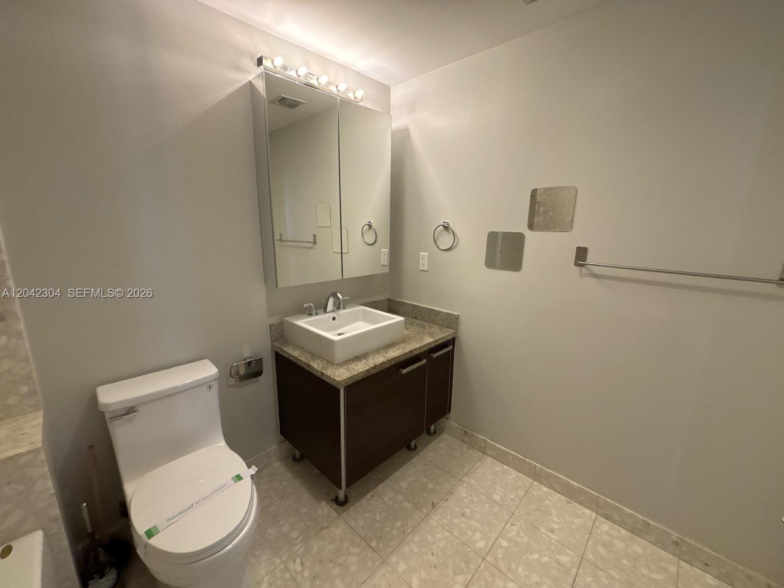 A bathroom features a floating vanity with a vessel sink, toilet, and mirrored medicine cabinet — 185 SW 7th St # 1410, Miami FL 33130, MIAMI, FL