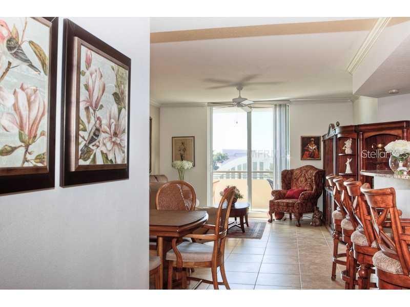 A dining area and living space feature tile floors, a ceiling fan, and balcony access — 800 N. TAMIAMI TRAIL UNIT 303, SARASOTA, FL