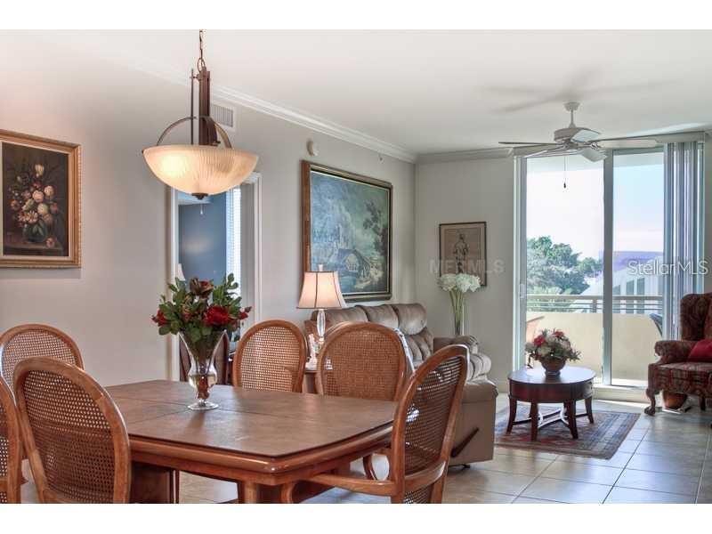 A dining area with a wooden table and chairs sits adjacent to a living room — 800 N. TAMIAMI TRAIL UNIT 303, SARASOTA, FL