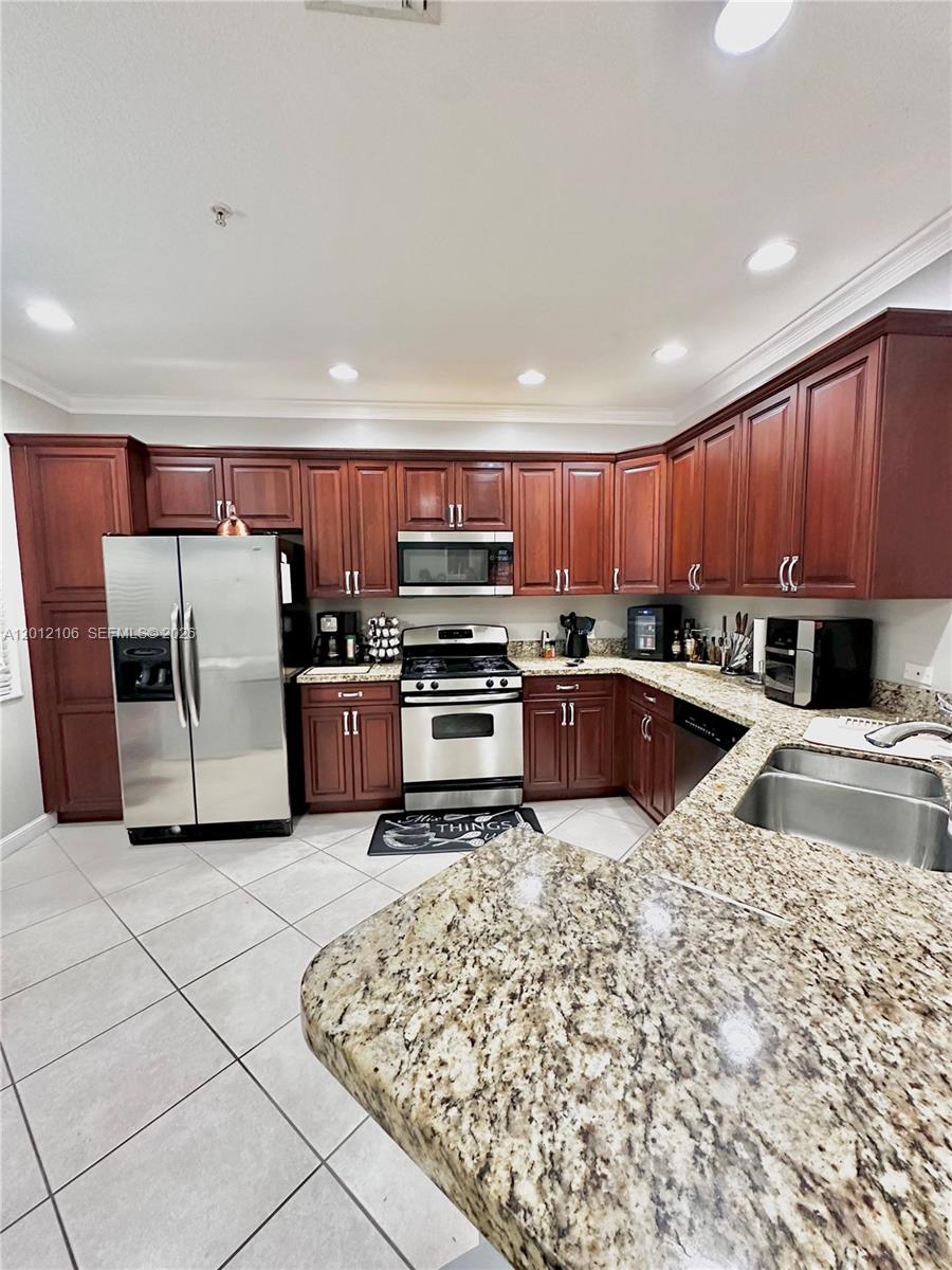 A kitchen features cherry wood cabinets, granite countertops, stainless steel appliances, and tile flooring — 2900 NW 125th Ave # 105, Sunrise FL 33323, SUNRISE, FL