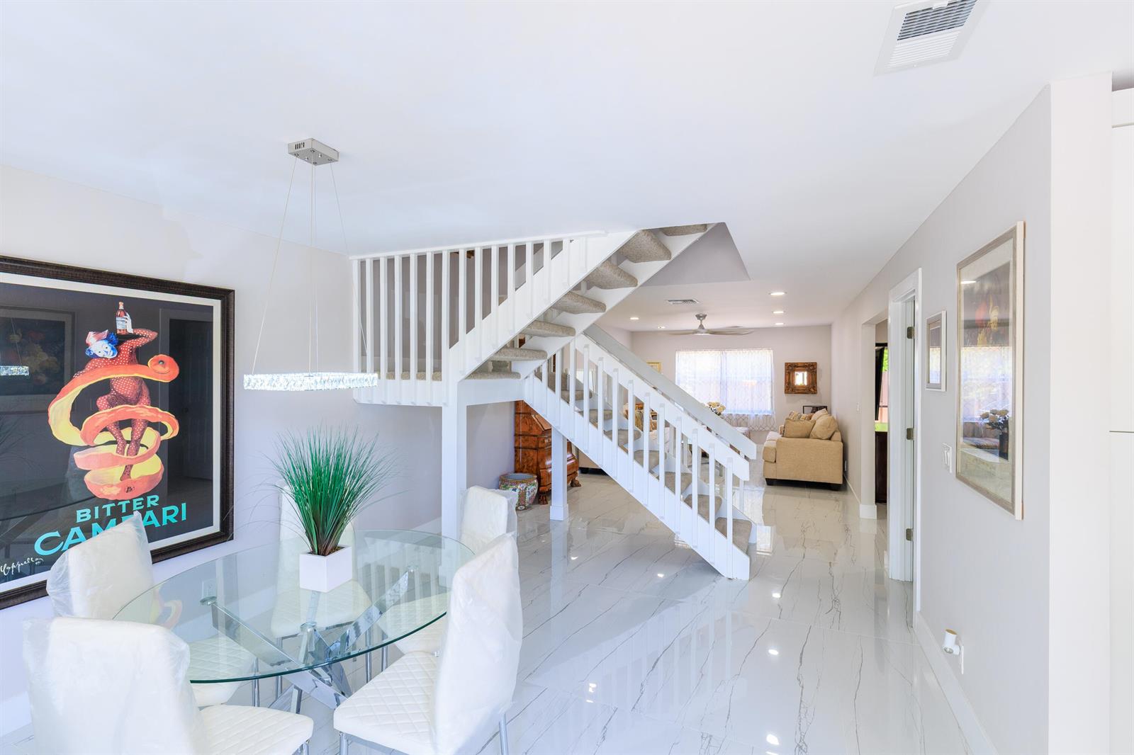 A dining area with a glass table and stairs leading to a living room — 5241 Jog Lane, Delray Beach FL 33484, DELRAY BEACH, FL