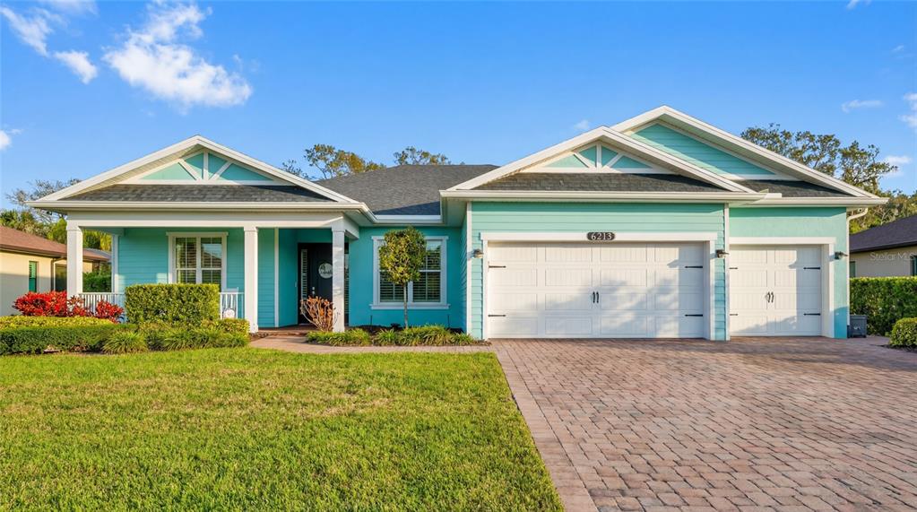 A turquoise single-story house features a white garage, a front porch, and a paved driveway — 6213 ARCADIA SQUARE, VERO BEACH, FL