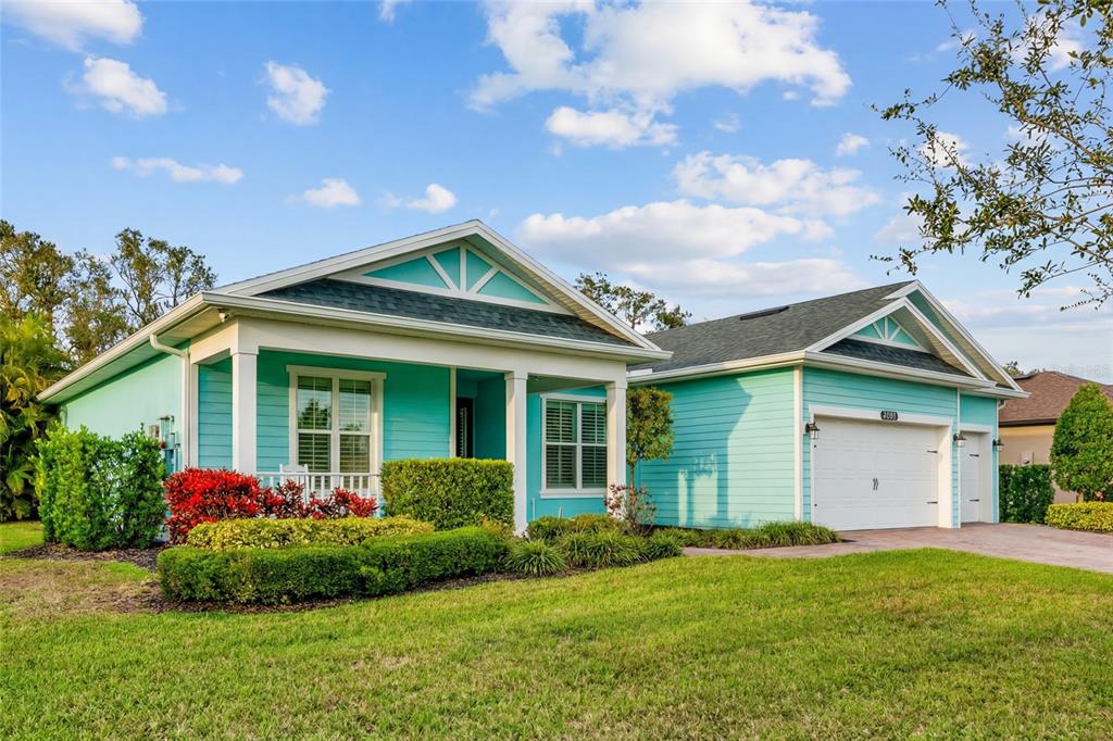 A light blue single-story house with a white garage and a front porch — 6213 ARCADIA SQUARE, VERO BEACH, FL