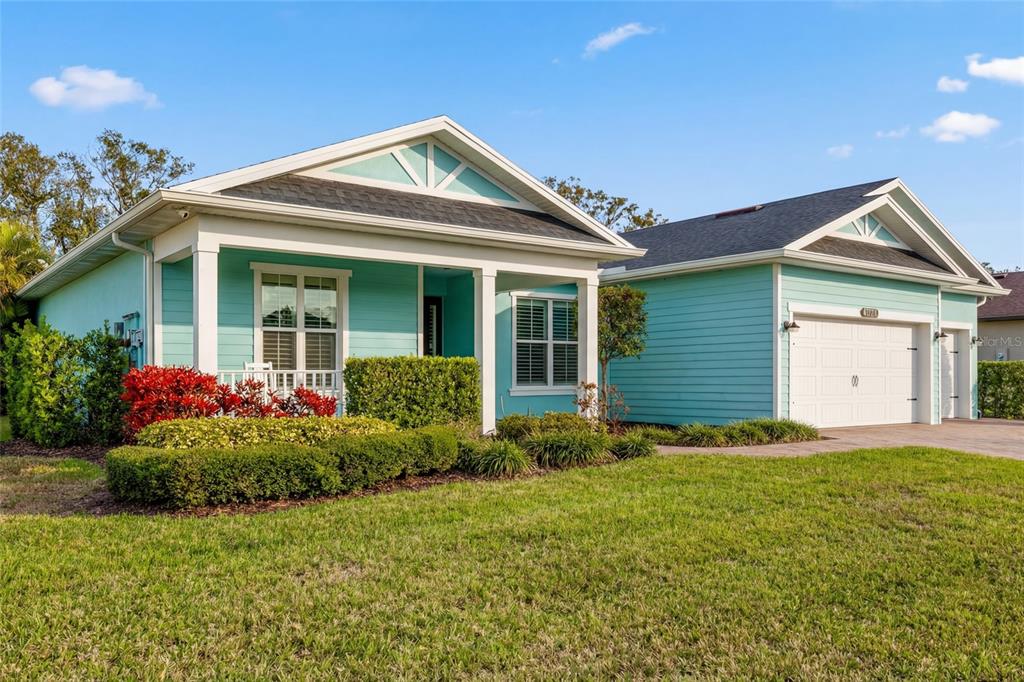 A light blue, single-story house with a white garage and a front porch — 6213 ARCADIA SQUARE, VERO BEACH, FL