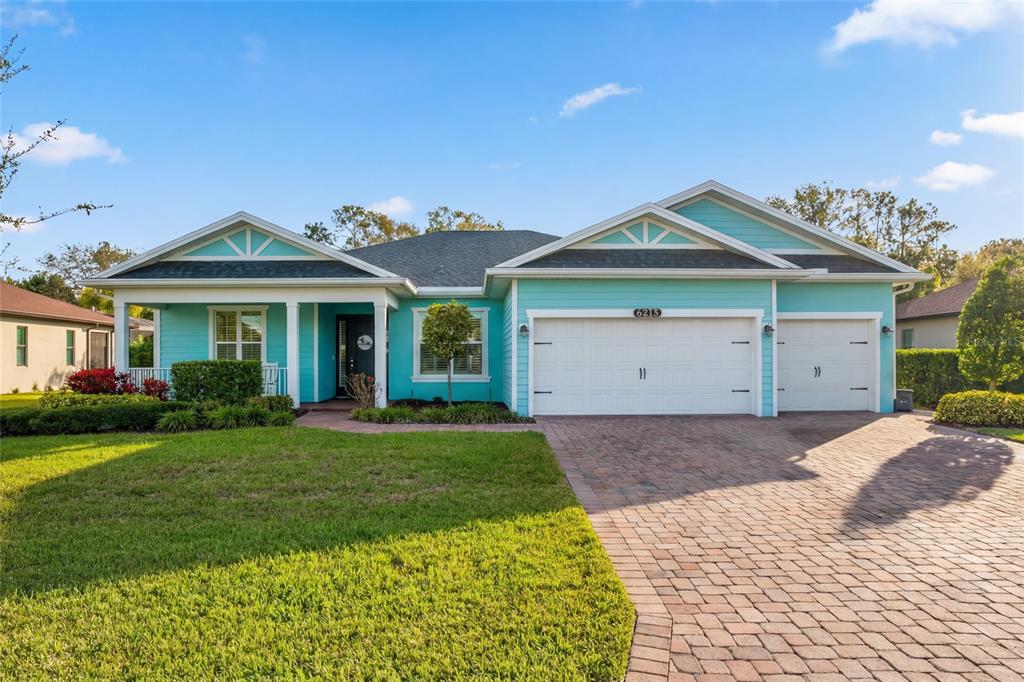 A turquoise single-story house features a white garage, a front porch, and a brick driveway — 6213 ARCADIA SQUARE, VERO BEACH, FL
