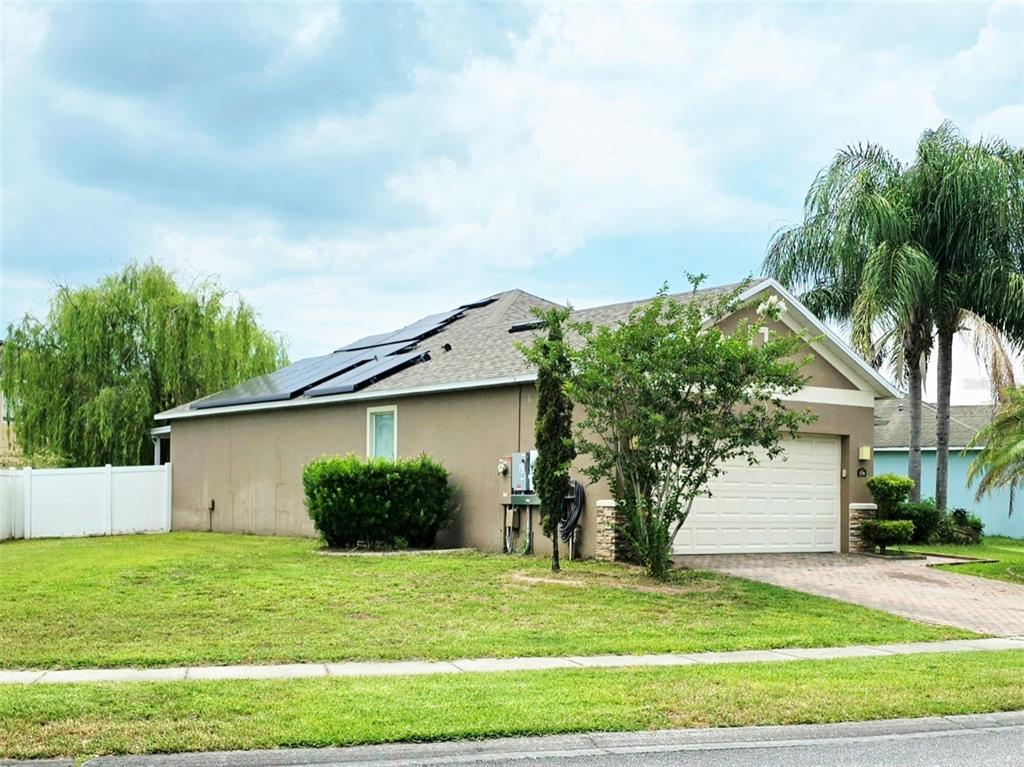 A single-story house with a tan exterior, a garage, and solar panels on the roof — 1710 PLANTATION POINTE DRIVE, ORLANDO, FL