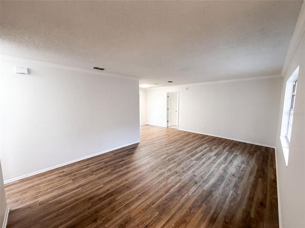 An empty room features white walls, a textured ceiling, and wood-look flooring — 8310 ROLLING LOG DRIVE, ORLANDO, FL
