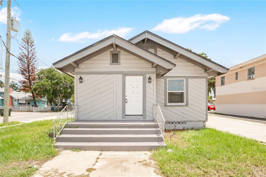 A single-story house with gray wood siding, a white front door, and concrete steps — 547 N RIDGEWOOD AVENUE, DAYTONA BEACH, FL