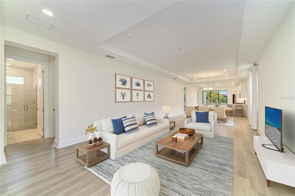 A living room features light wood flooring, a white sofa, a coffee table, and artwork — 5290 BARNETT CIRCLE, BRADENTON, FL