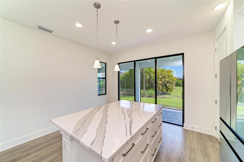 A kitchen island with a marble-patterned countertop sits before sliding glass doors leading outside — 5290 BARNETT CIRCLE, BRADENTON, FL