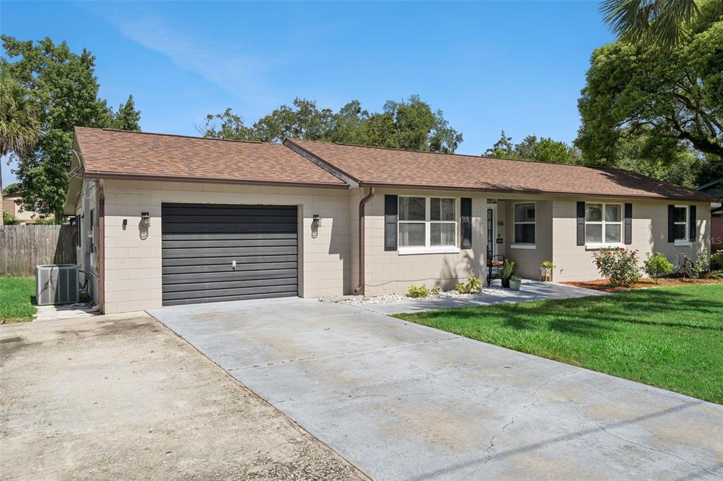 A single-story house with a concrete block exterior, a brown roof, and a concrete driveway — 106 ALANO ROAD, DEBARY, FL