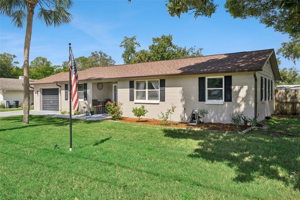 A single-story house with beige siding, a brown roof, and a front lawn with a flagpole — 106 ALANO ROAD, DEBARY, FL