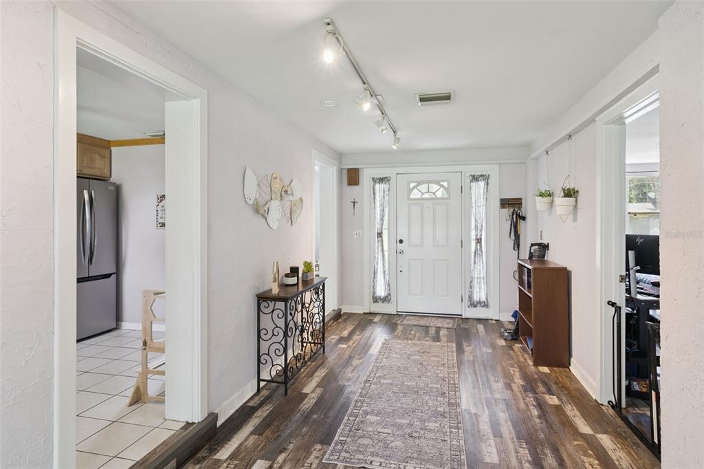 A bright entryway features wood-look flooring, a white front door, and a track lighting fixture — 106 ALANO ROAD, DEBARY, FL