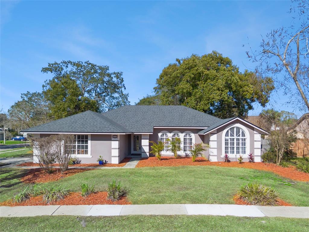A single-story house with a gray exterior, a dark shingled roof, and a front lawn — 692 ROCHESTER STREET, OVIEDO, FL