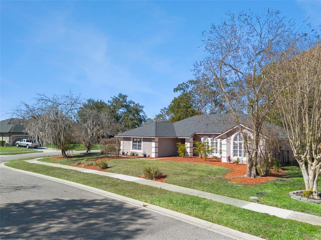 A single-story house with a gray roof and tan exterior sits on a corner lot — 692 ROCHESTER STREET, OVIEDO, FL