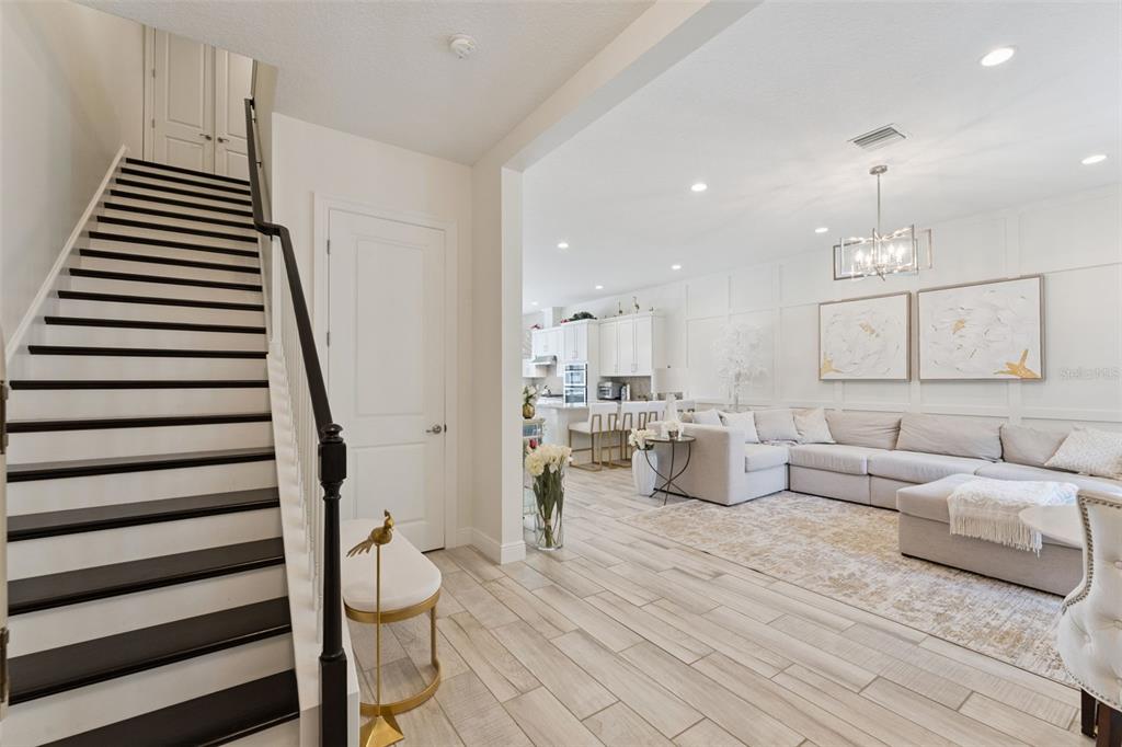 A staircase with dark treads leads to an open-concept living room with white cabinetry — 8932 BISMARCK PALM DRIVE, WINTER GARDEN, FL