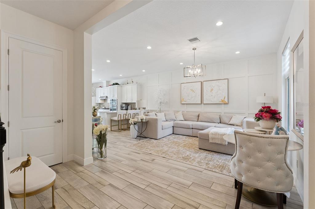 A bright, open-concept living room features light wood-look tile flooring and white board-and-batten walls — 8932 BISMARCK PALM DRIVE, WINTER GARDEN, FL