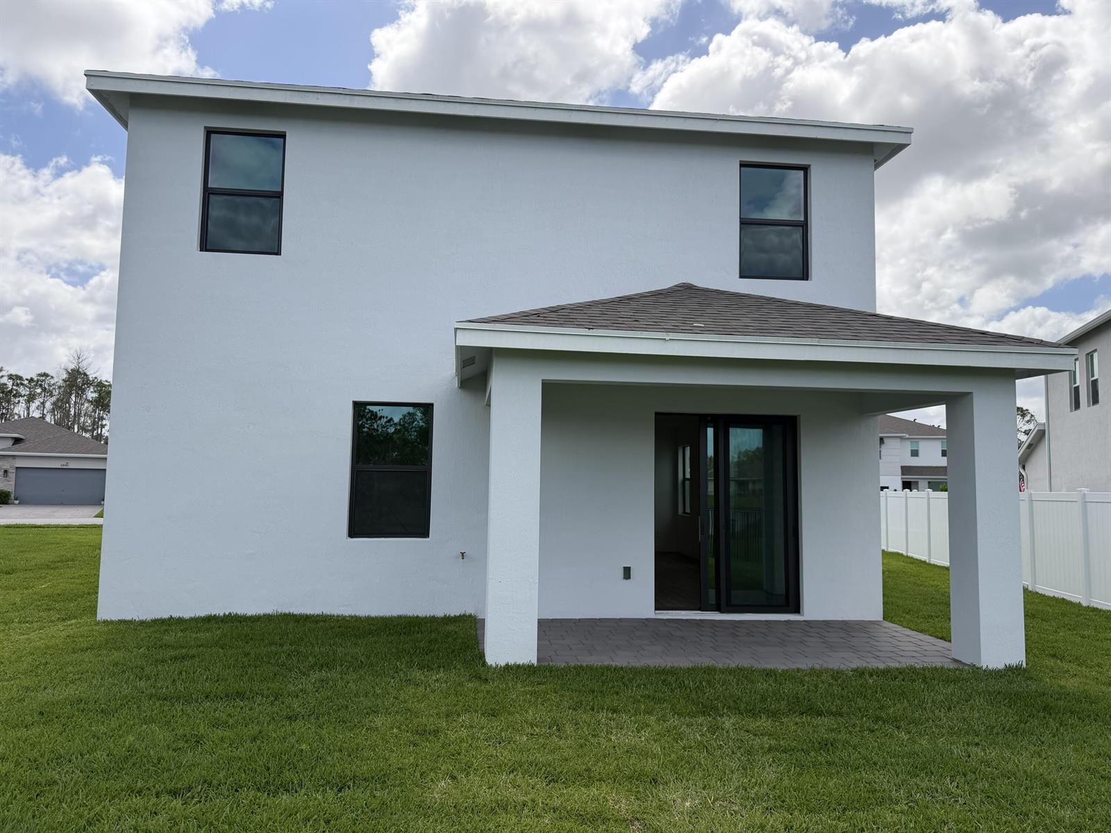 The back exterior of a two-story house features a covered patio and a grassy yard — 6781 SE Park Trace Drive, Stuart FL 34997, STUART, FL